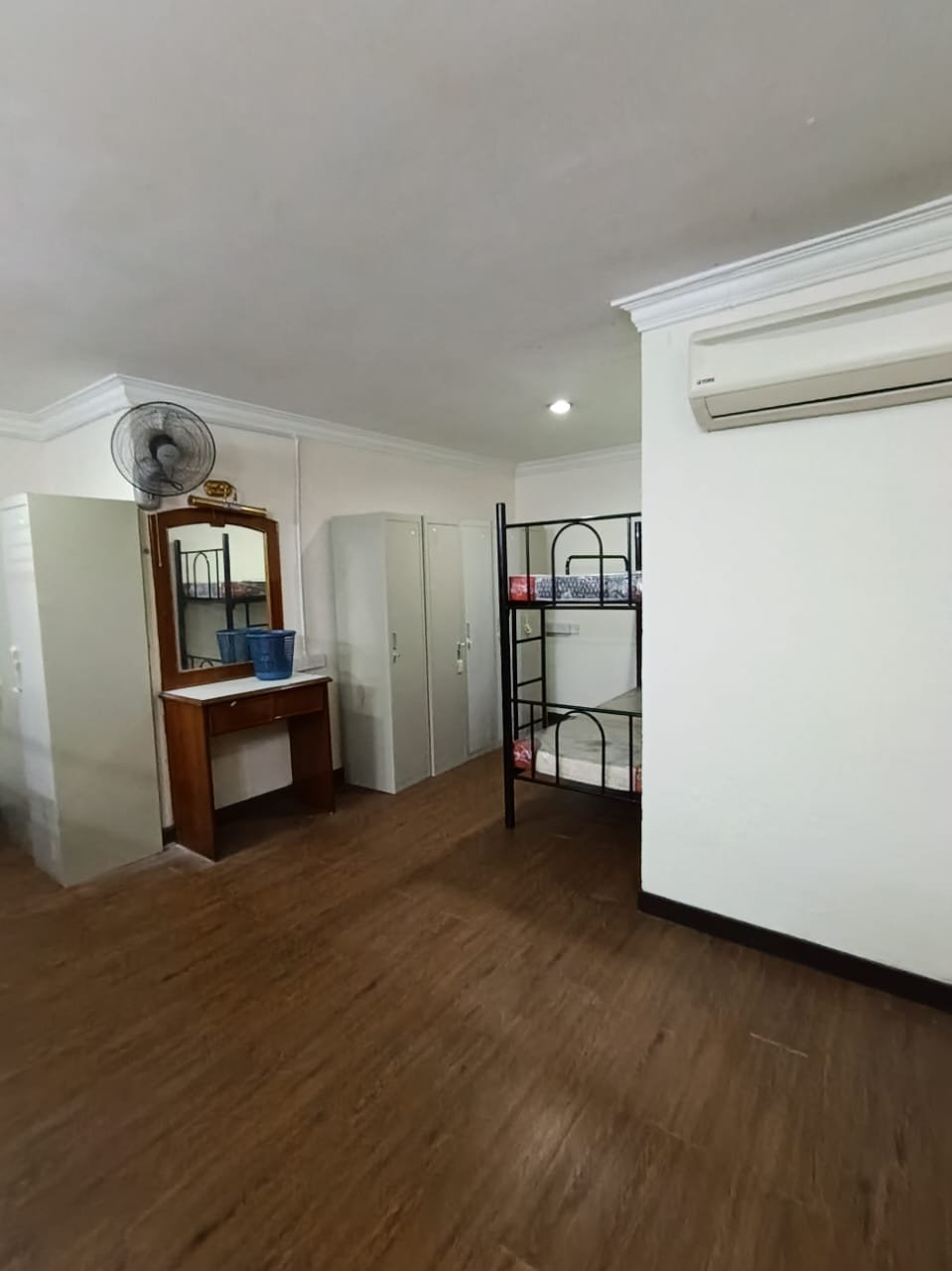 A spacious hostel room with new flooring, a dressing table, storage lockers, and a bunk bed