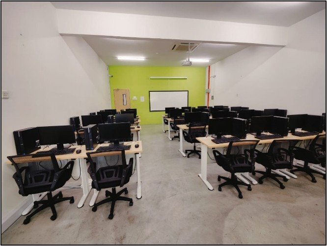 The computer laboratory seen from the back, with workstations facing a whiteboard on a lime green wall