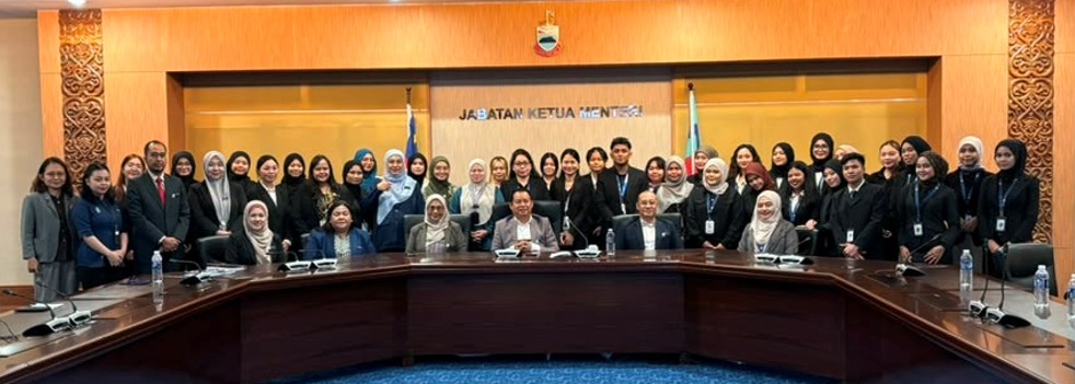 A large group of students and staff posing together in the Jabatan Ketua Menteri meeting hall