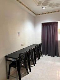 A row of new study tables and chairs along a hostel room wall, beside a curtained window