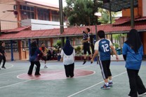 Students playing netball on an outdoor court, wearing team bibs