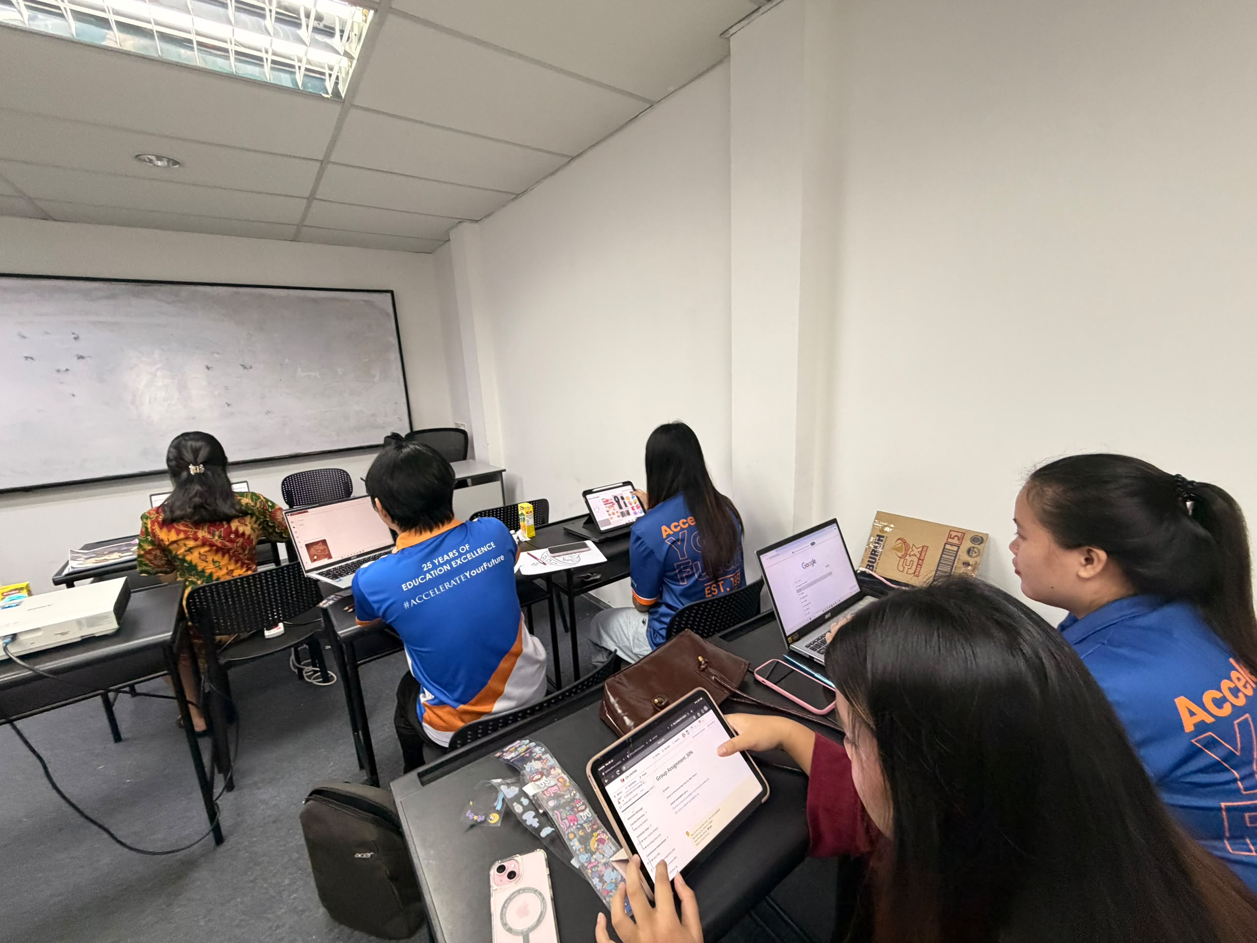 Students working on laptops and tablets in a classroom, connected to campus Wi-Fi