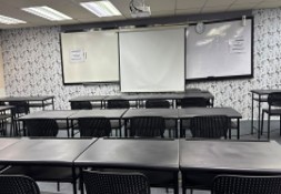 A second refurbished classroom, with new tables and chairs facing a whiteboard on a patterned wall
