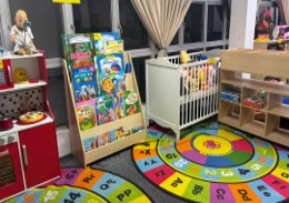 The Diploma in Early Childhood Education lab, with a book display, a cot, toy storage, and an alphabet rug