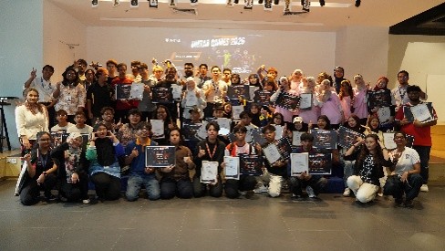 A large group of students and staff posing together with certificates at the closing ceremony