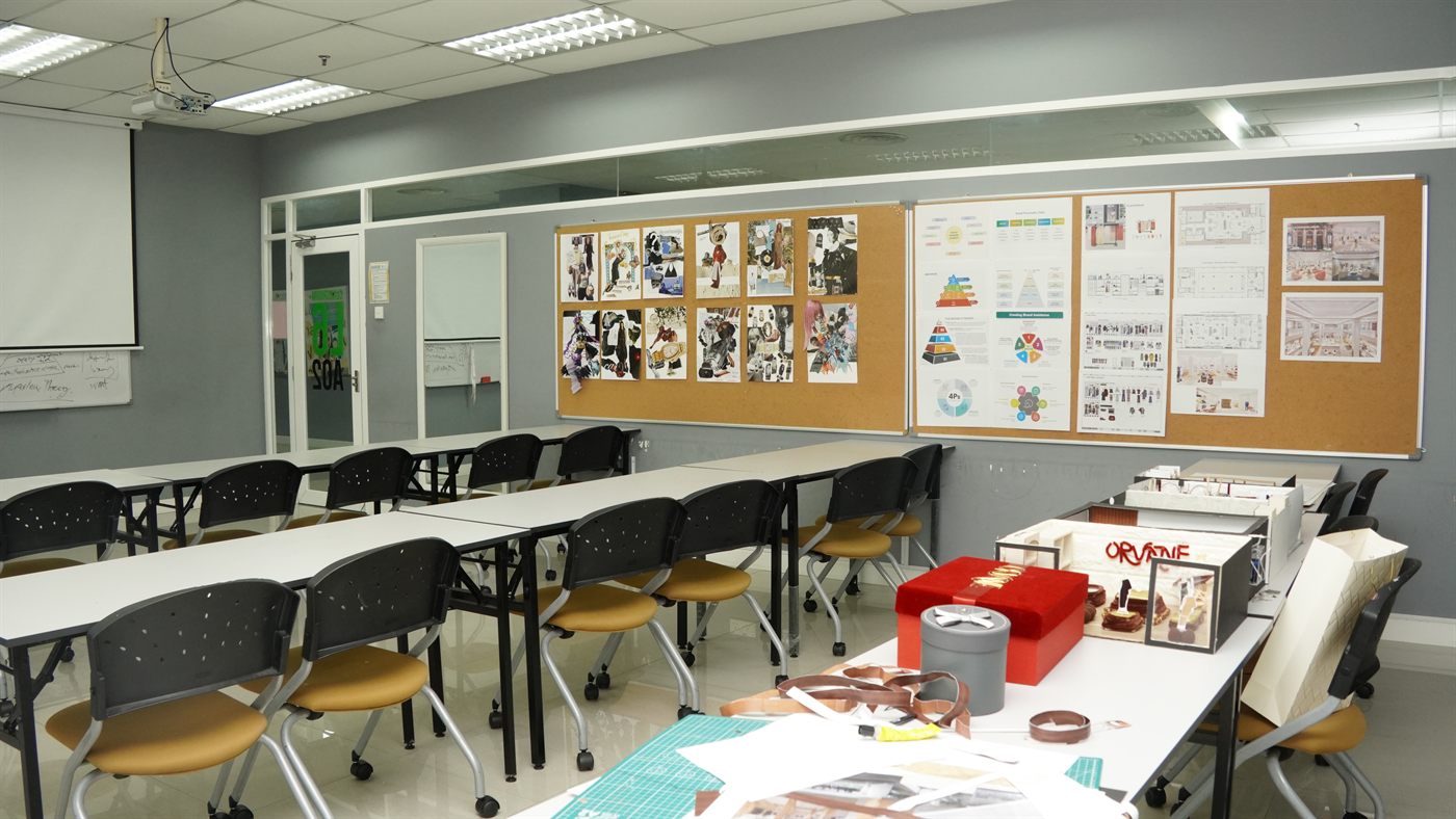 A studio classroom with mood boards and design presentation panels pinned along the wall, and scale models on the tables