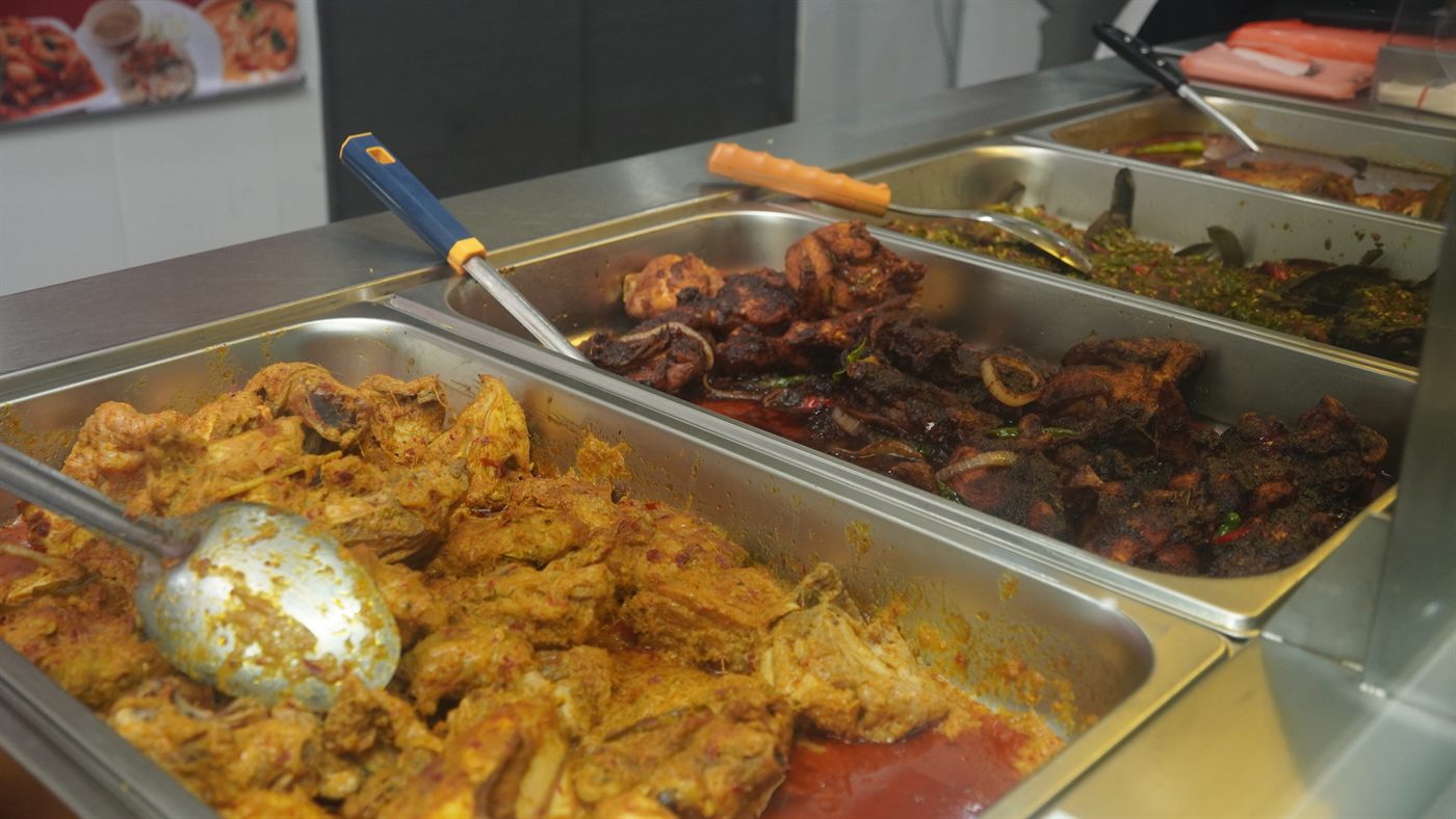 Close-up of serving trays filled with curried chicken and other cooked dishes