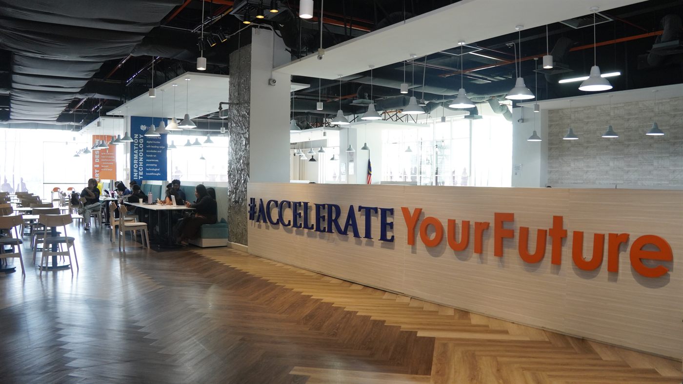 The wide café seating hall, with booth seating and an #AccelerateYourFuture wall