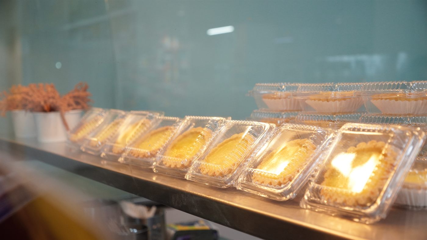 A row of packaged egg tarts arranged along the café counter