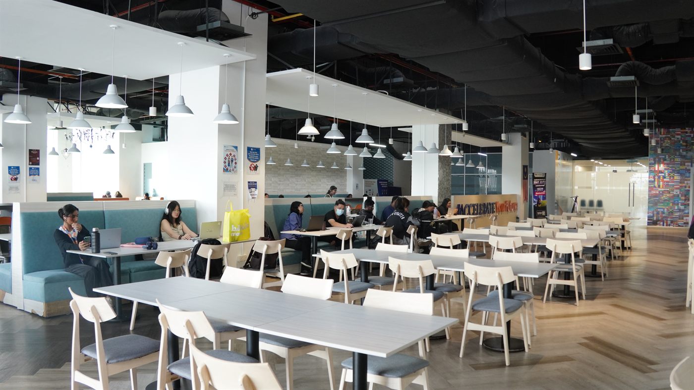 Students sitting with laptops at tables in the café during the day