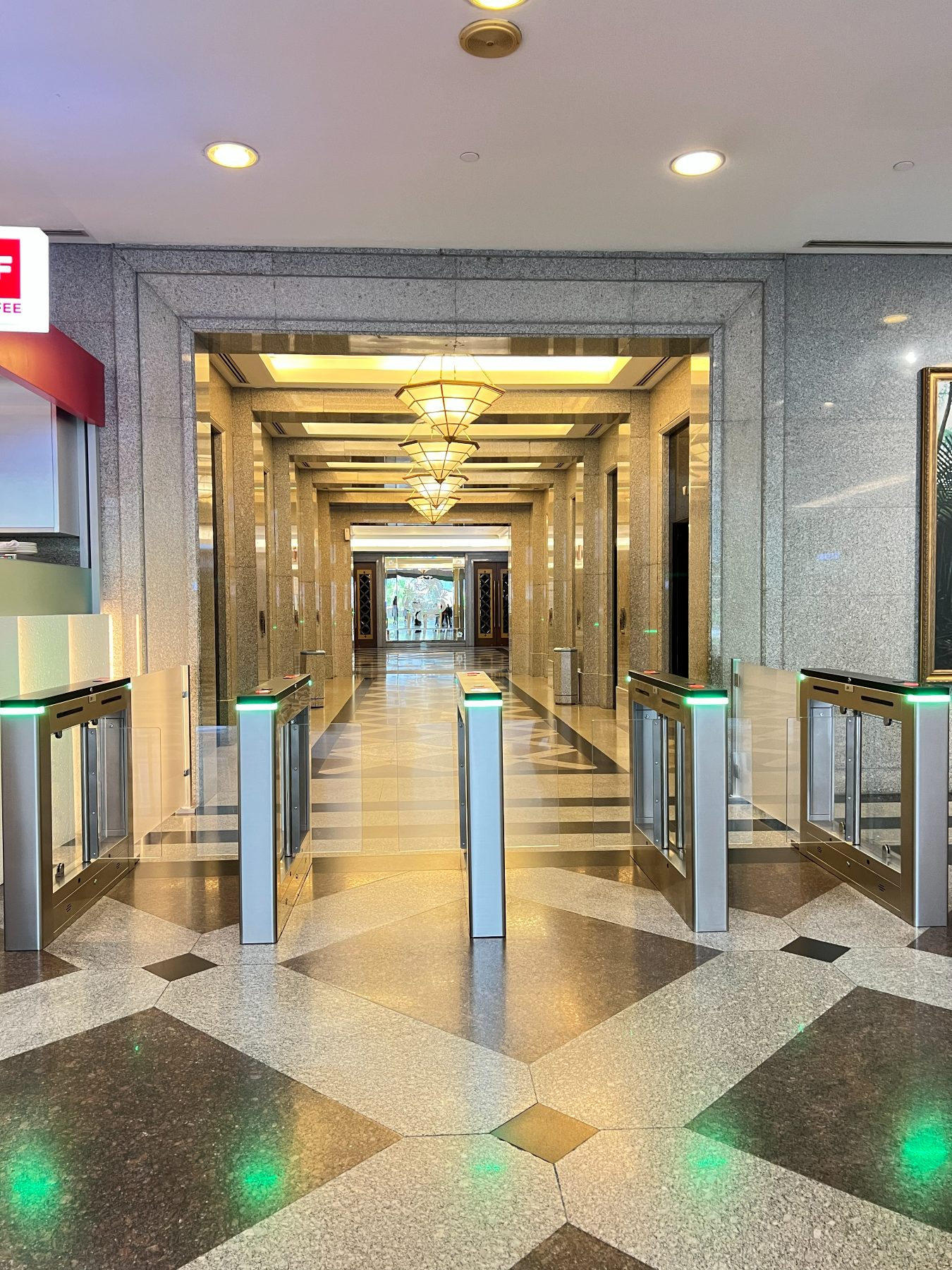 Access-control gates installed across the Level 1 lobby entrance, their indicator lights showing green, with the lift lobby beyond