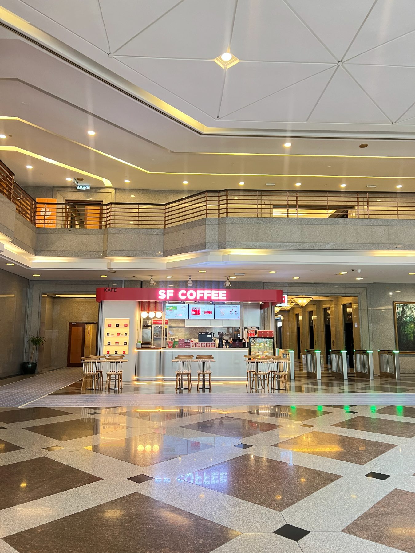 The SF Coffee counter in the building lobby, with menu screens above the bar and wooden stools along the front