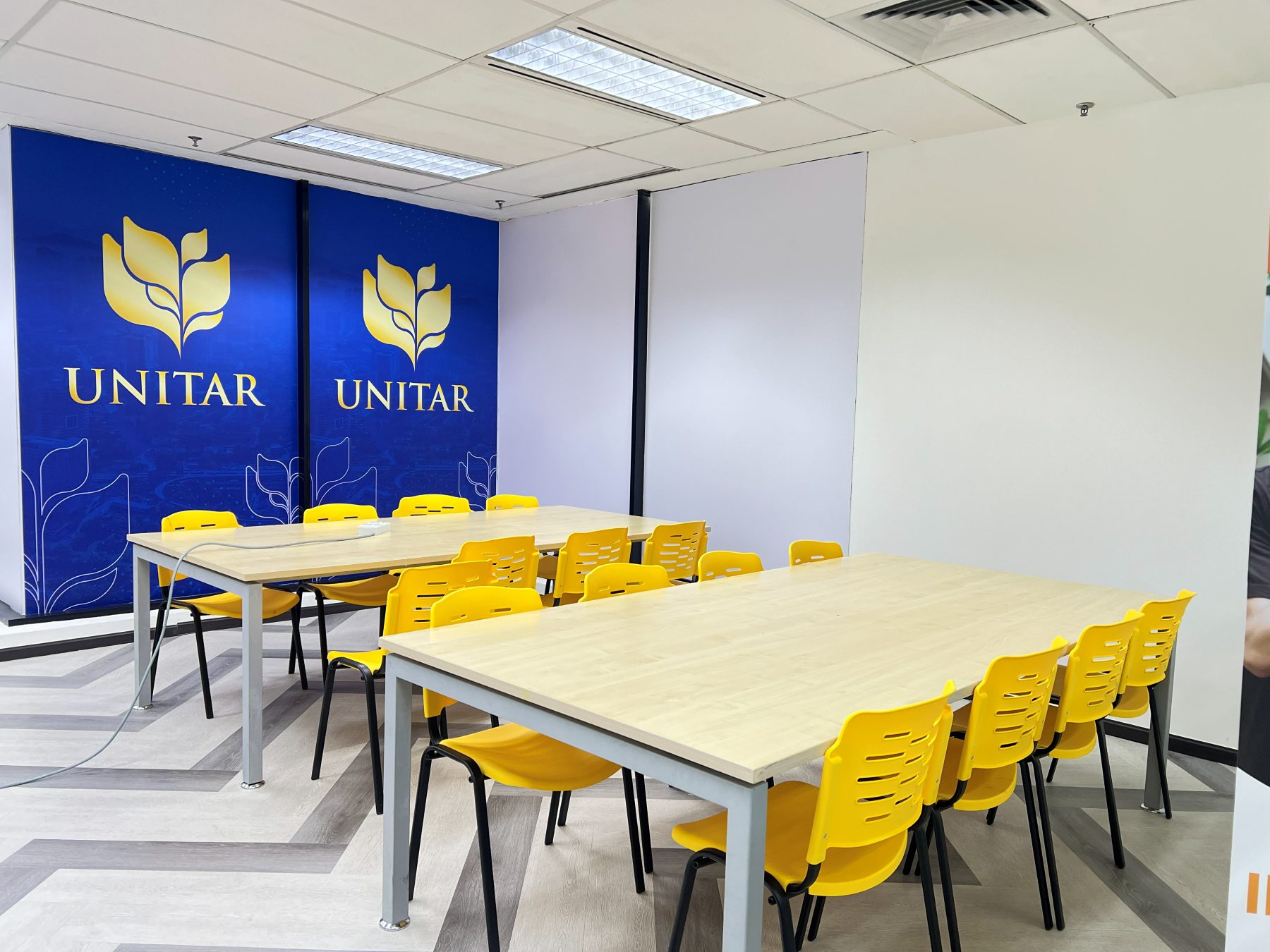 Two long study tables surrounded by yellow chairs, in front of a blue UNITAR wall panel